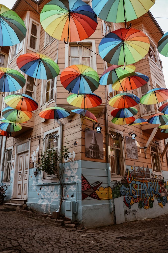 Vibrant umbrellas float above a graffitied street in Istanbul, creating a colorful canopy.
